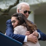 President Biden hugs a woman at a podium