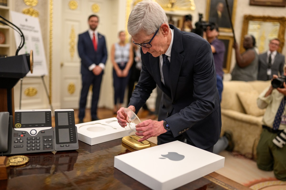 Apple CEO Tim Cook sets up an engraved glass Apple disc on the Resolute Desk before President Donald Trump announces a $100 billion investment in the U.S., Wednesday, August 6, 2025, in the Oval Office. (Official White House Photo by Daniel Torok)