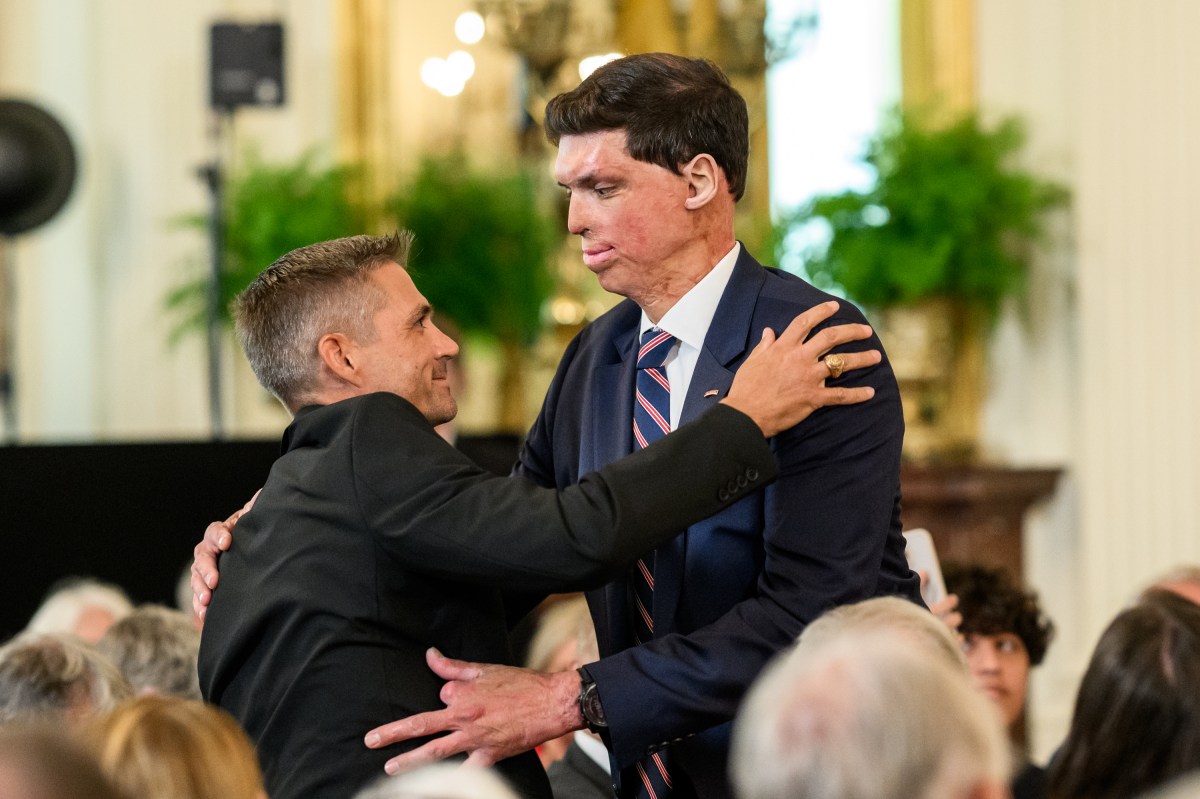 Kevin Jensen hugs Under Secretary for Memorial Affairs Samuel Brown as President Donald Trump delivers remarks at a National Purple Heart Day ceremony in the East Room, Thursday, August 7, 2025. (Official White House Photo by Joyce N. Boghosian)