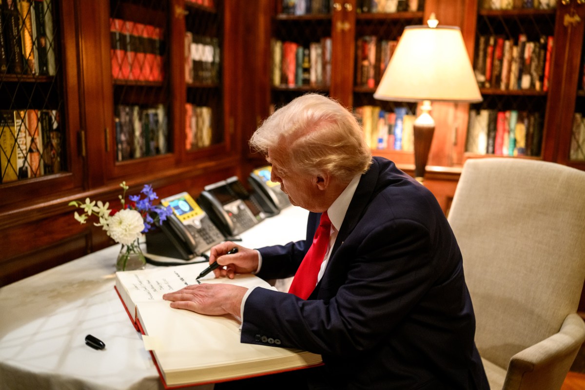 President Donald Trump signs the guest book at the ambassador’s residence in Tokyo, Japan on Tuesday, October 28, 2025, as Secretary of Commerce Howard Lutnick, Ambassador George Glass, and his wife, Mary Glass, look on. (Official White House Photo by Molly Riley)