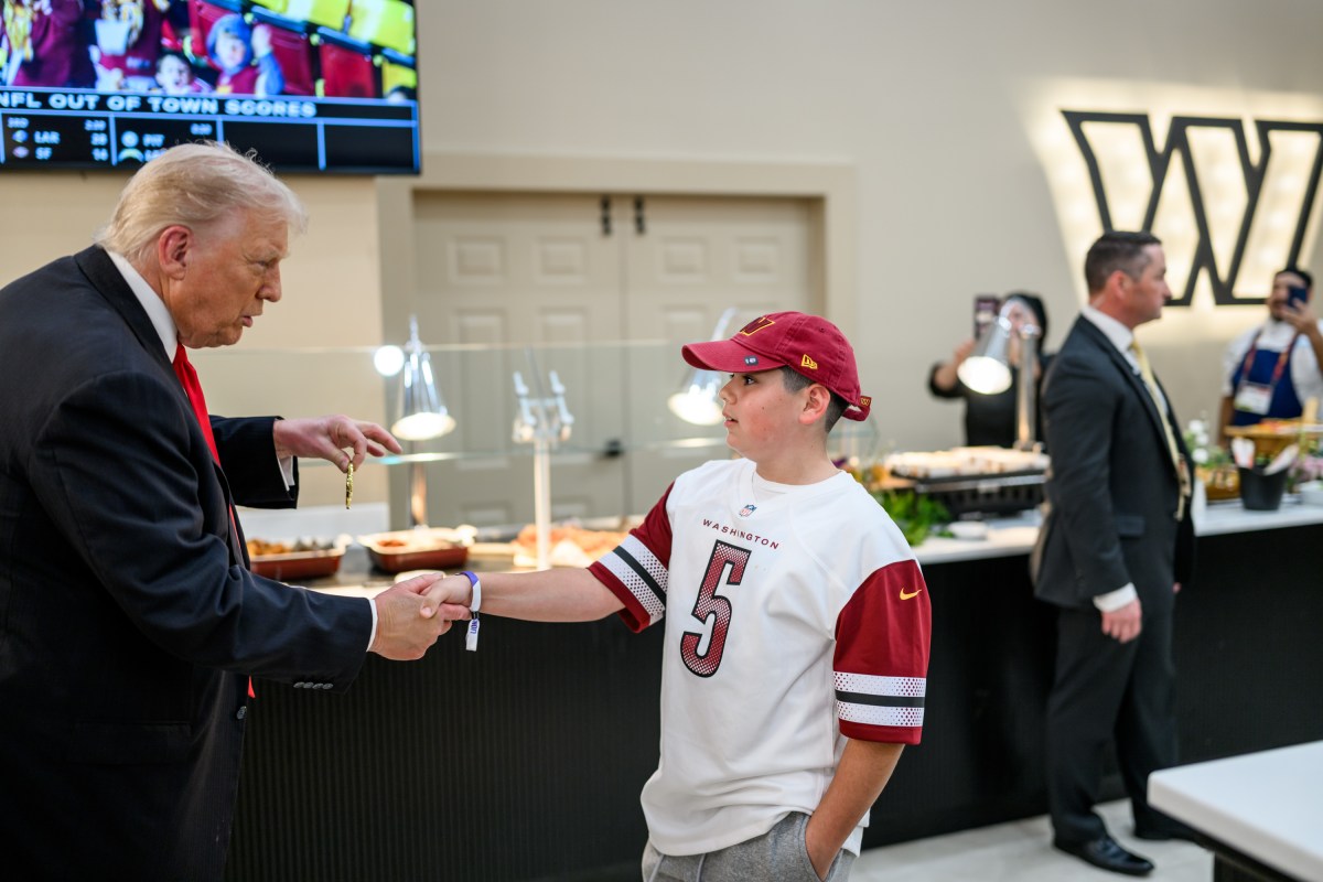 President Donald Trump presents a Presidential Challenge Coin to a young fan as the Washington Commanders take on the Detroit Lions at Northwest Stadium in Landover, Maryland, Sunday, November 9, 2025. (Official White House Photo by Daniel Torok)