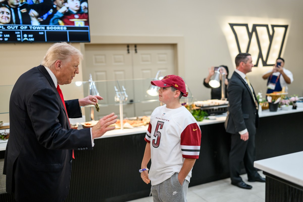 President Donald Trump presents a Presidential Challenge Coin to a young fan as the Washington Commanders take on the Detroit Lions at Northwest Stadium in Landover, Maryland, Sunday, November 9, 2025. (Official White House Photo by Daniel Torok)
